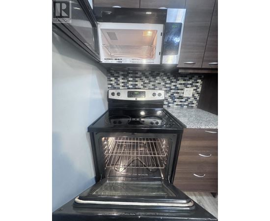 A black oven with the door open is in a kitchen.