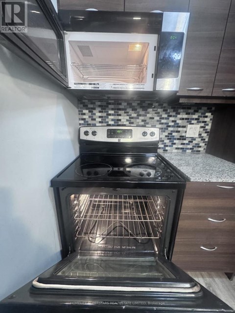 A black oven with the door open is in a kitchen.