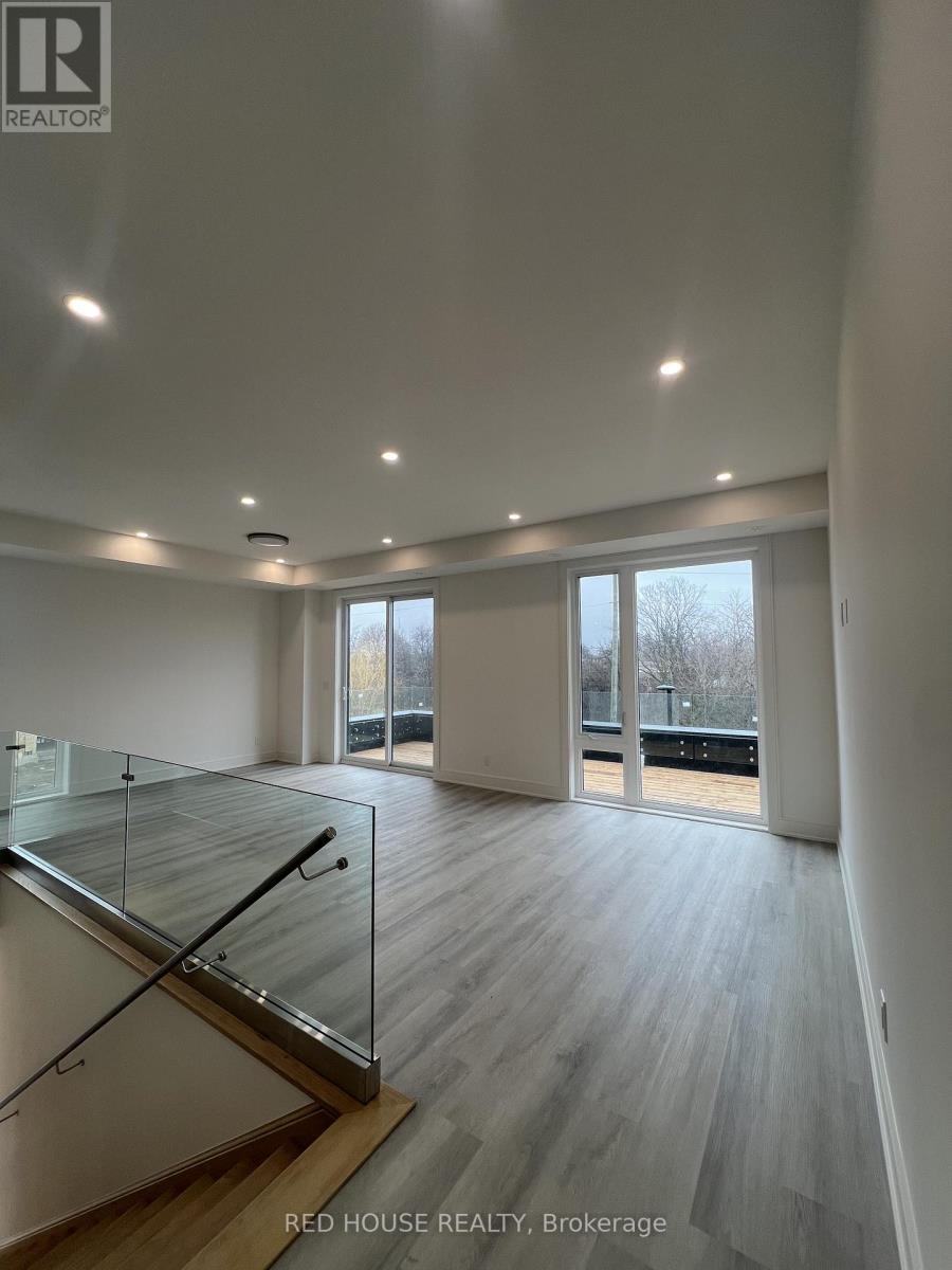 A spacious room with a glass staircase and wooden flooring.