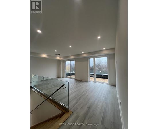A spacious room with a glass staircase and wooden flooring.