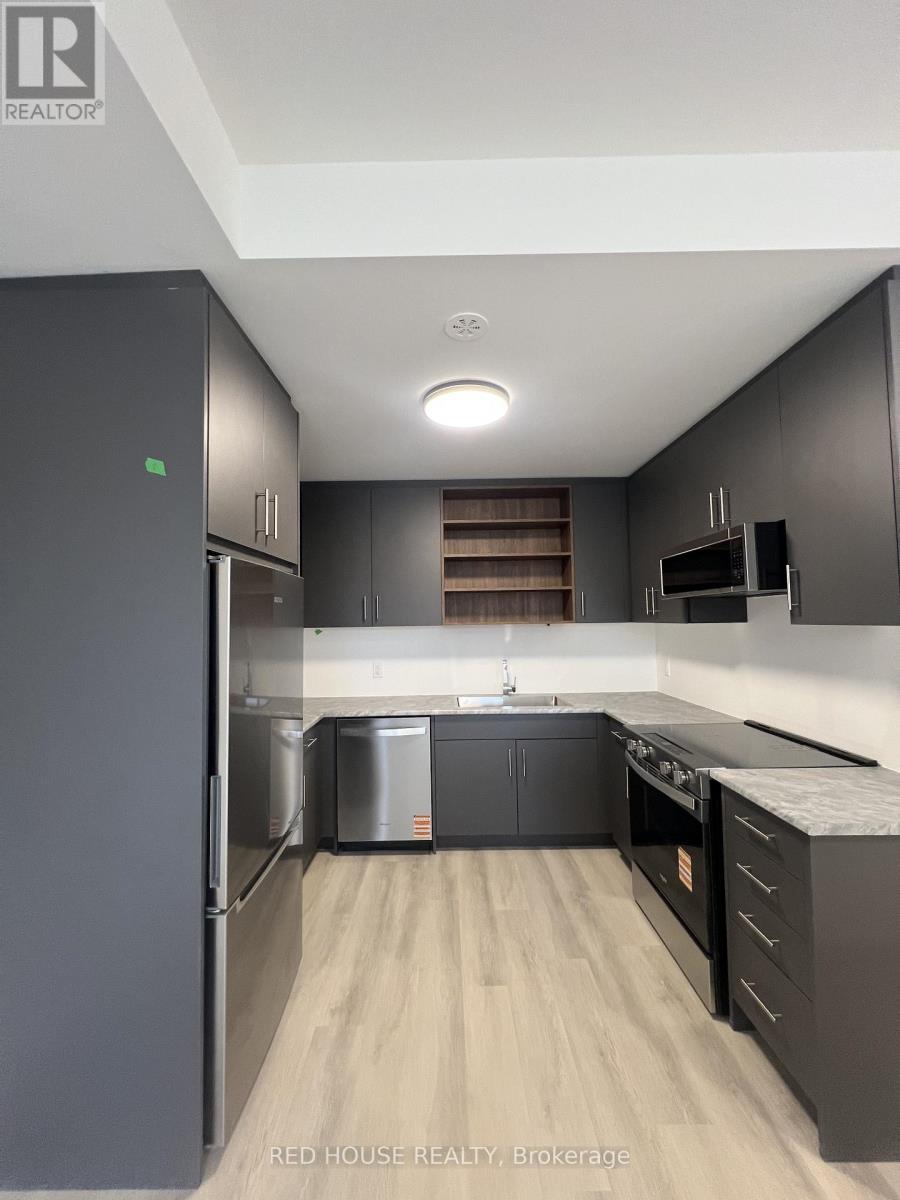 A modern kitchen with dark wood cabinets and a refrigerator.