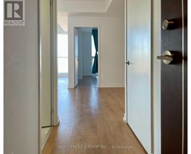 A hallway with wooden floors and white walls leading to a blue door.