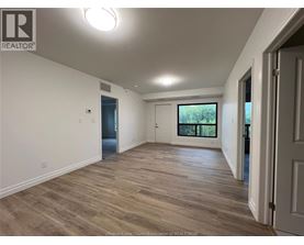 A spacious room with wooden flooring and white walls.