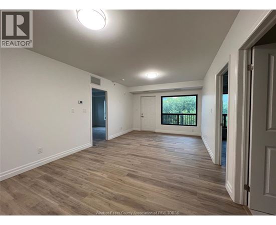 A spacious room with wooden flooring and white walls.