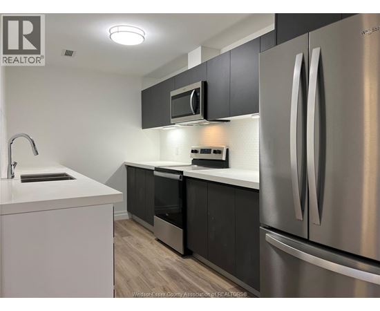 A kitchen with a stainless steel refrigerator, microwave, and oven.