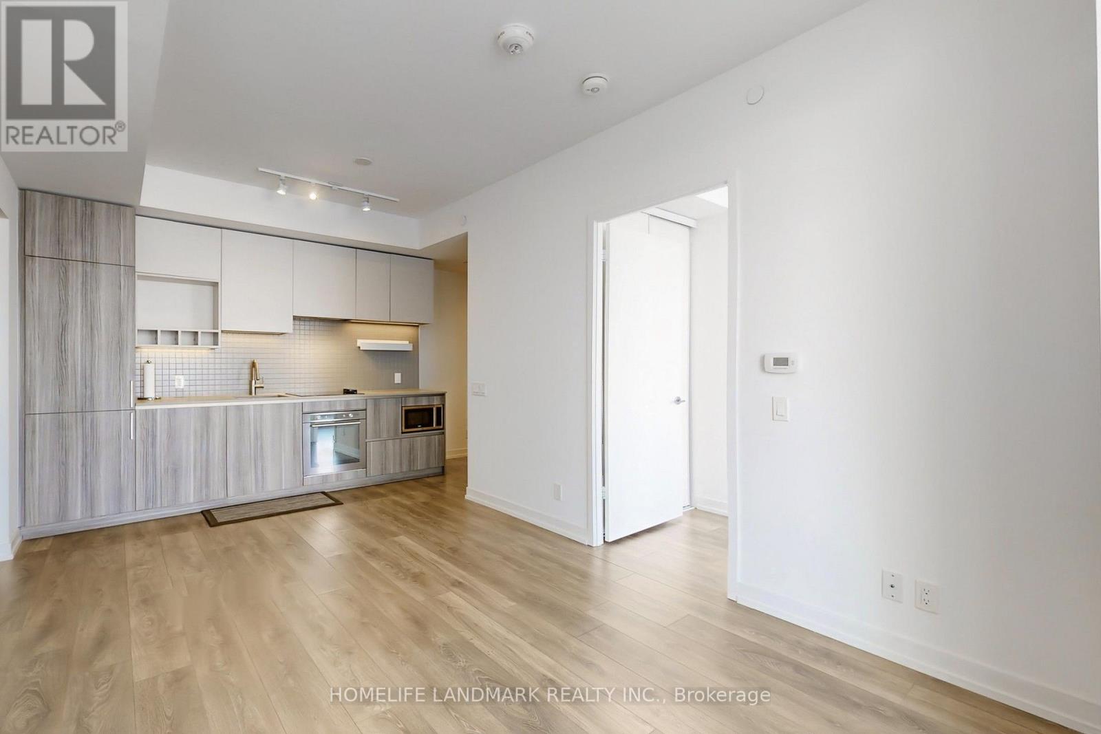 A spacious kitchen with white cabinets and a wooden floor.