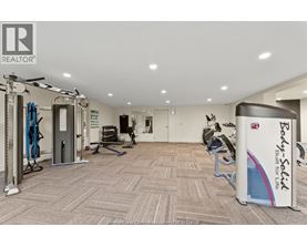 A gym room with a variety of equipment including a treadmill, weights, and a bench press.