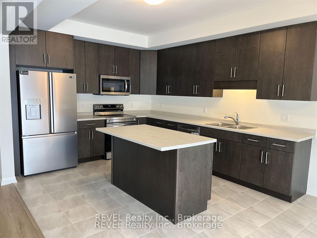 A kitchen with a refrigerator, microwave, oven, sink, and cabinets.