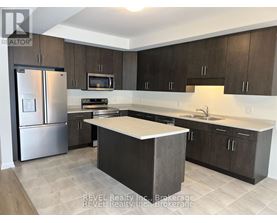 A kitchen with a refrigerator, microwave, oven, sink, and cabinets.
