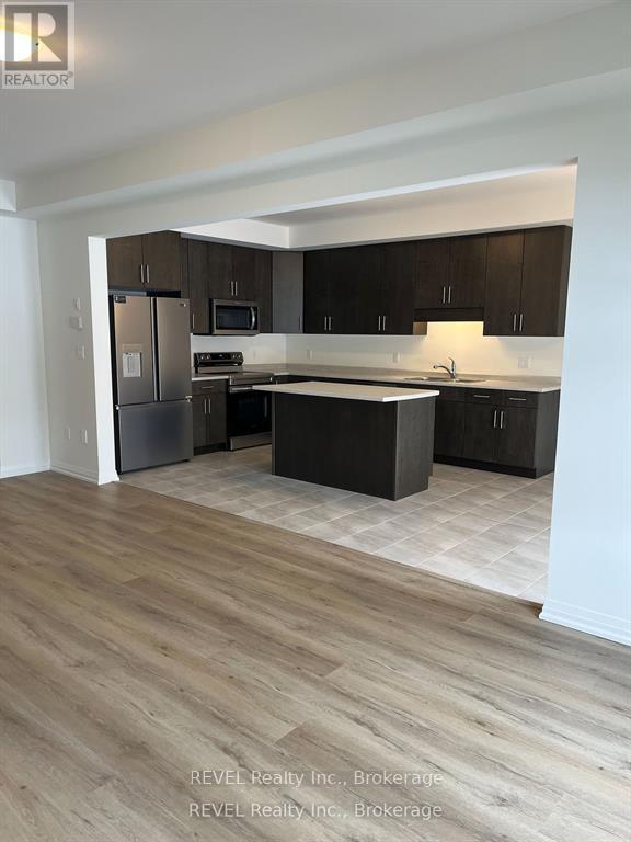 A kitchen with dark wood cabinets and a light wood floor.
