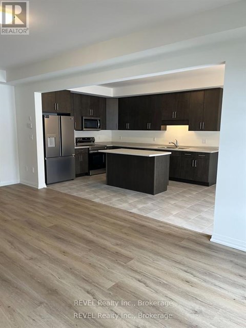 A kitchen with dark wood cabinets and a light wood floor.