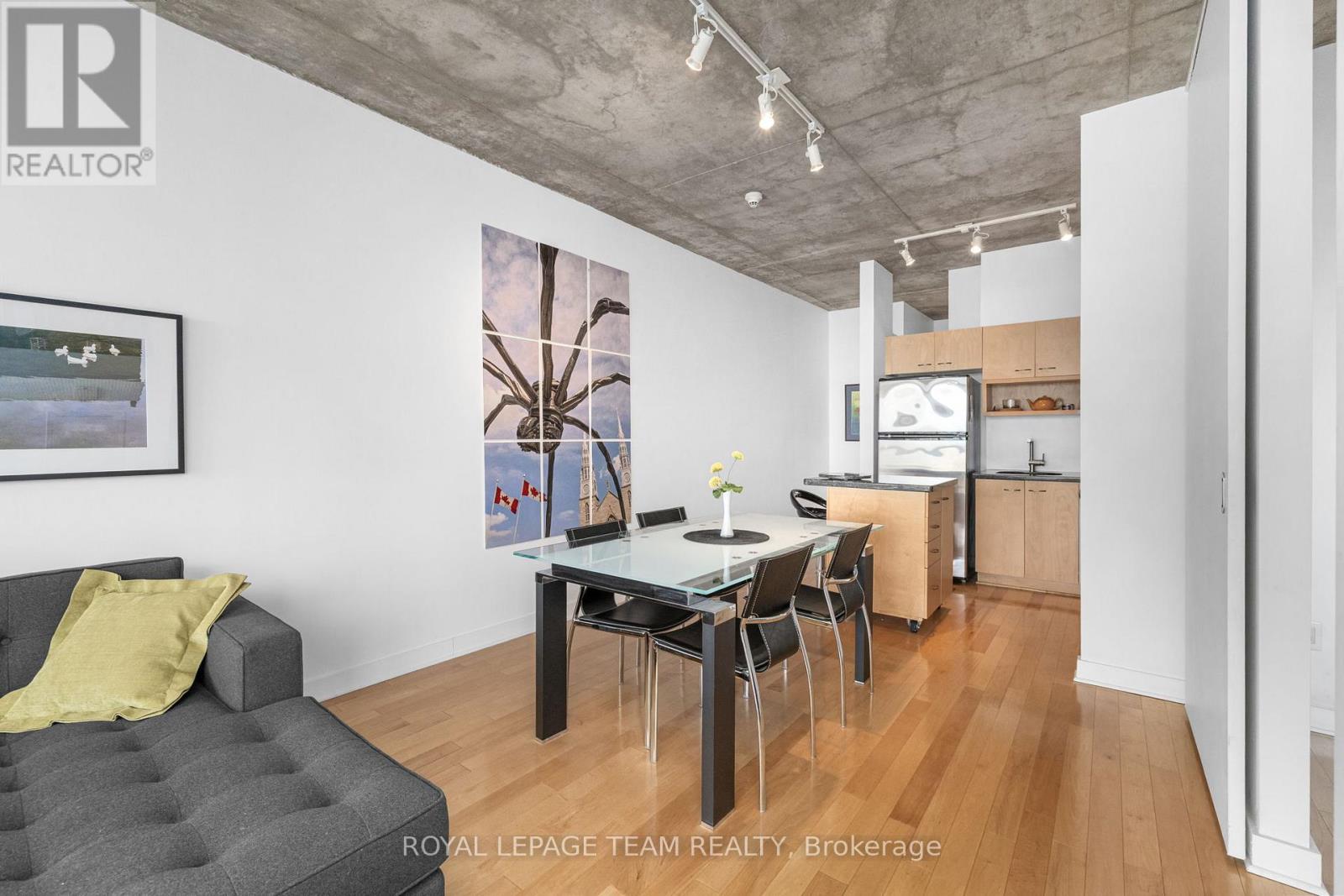 A modern living room with a grey sofa and a dining table with chairs.
