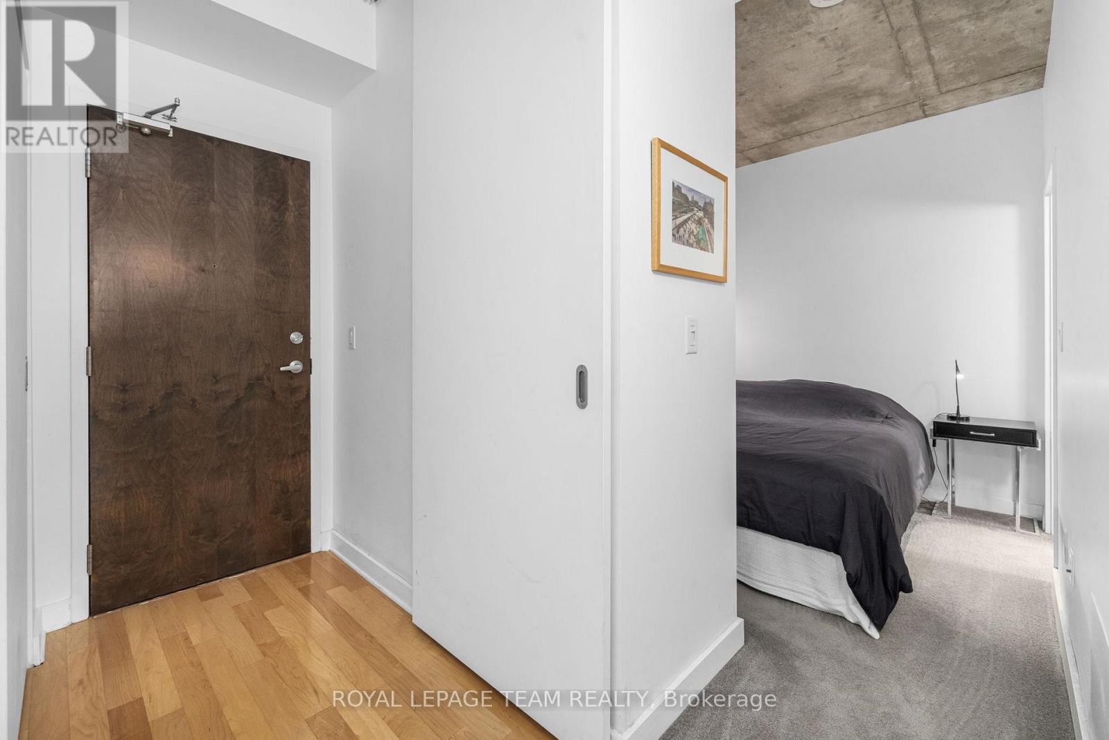 A bedroom with a bed, a nightstand and a picture on the wall.