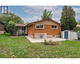 A house with a brown brick exterior and a white fence.