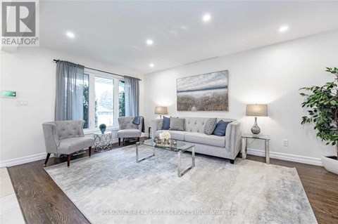 A living room with a grey couch, a grey armchair, a glass coffee table and a grey rug.