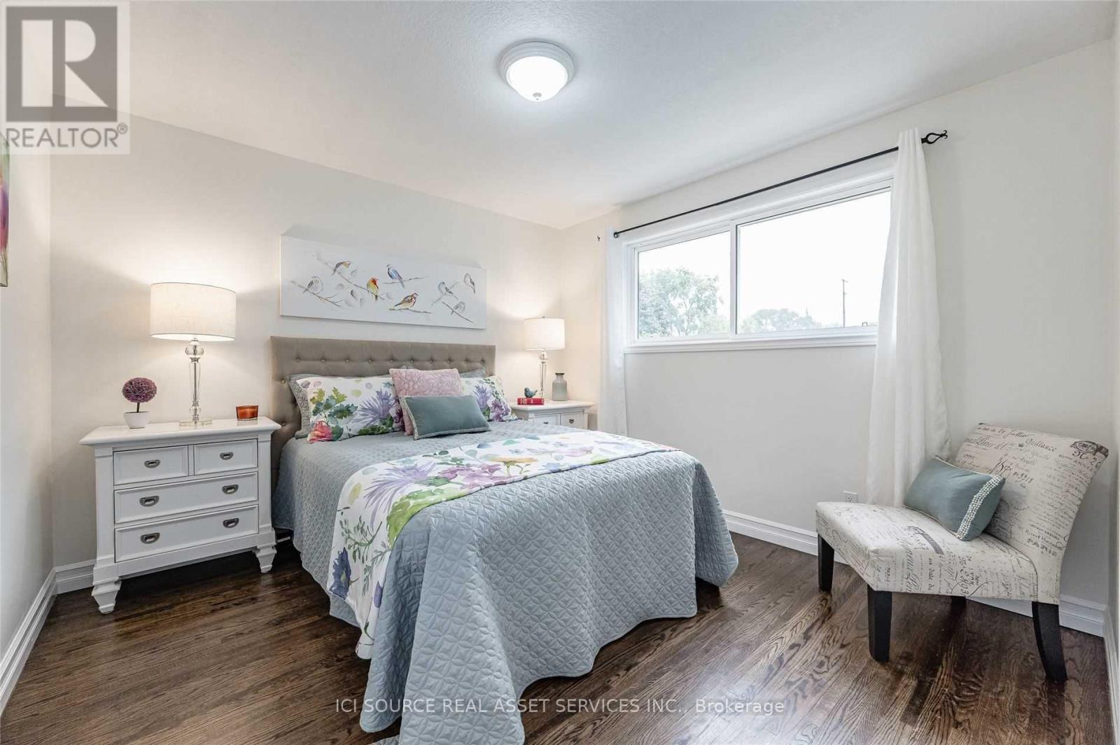 A bedroom with a bed, chair, and nightstand.