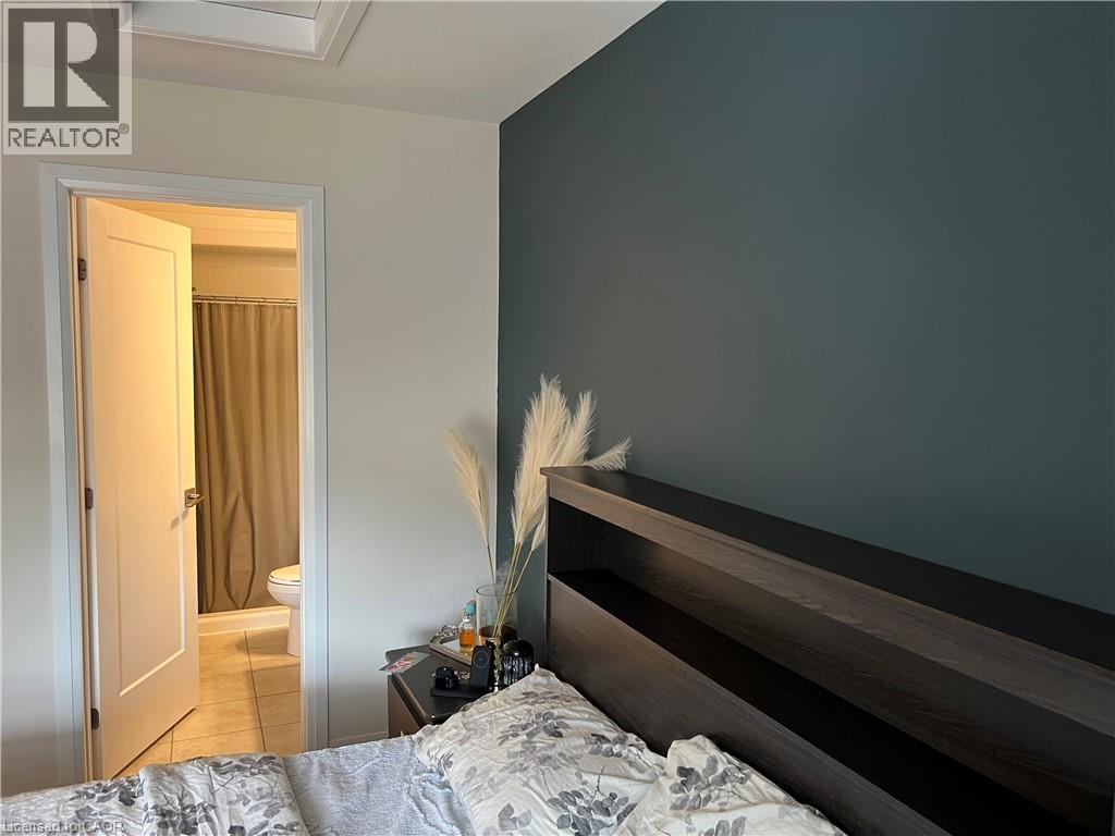 A bedroom with a bed, a nightstand with a lamp, and a feather on the wall.