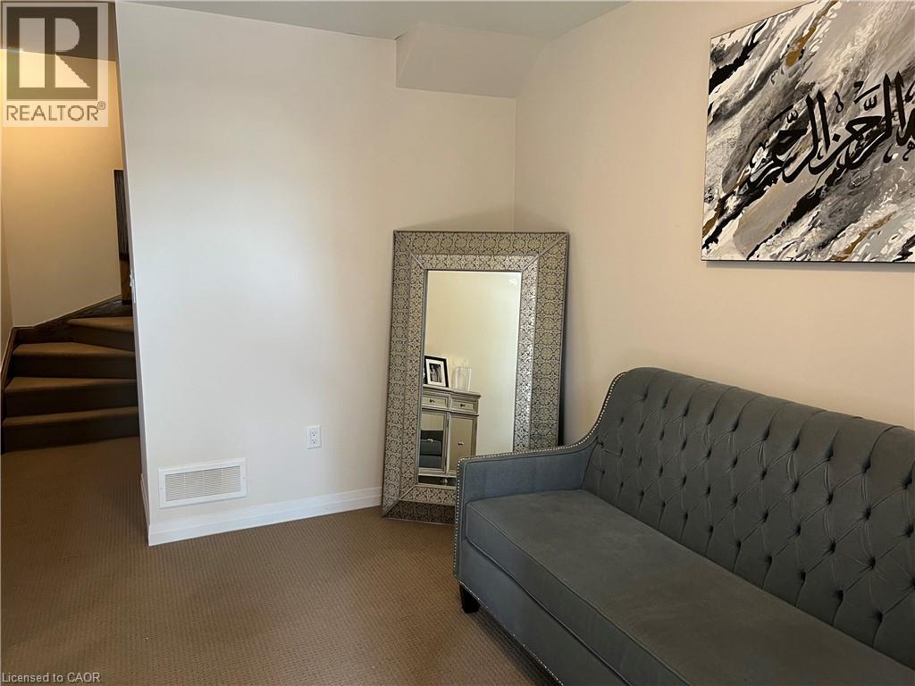 A grey couch sits in a living room with a mirror and a painting on the wall.
