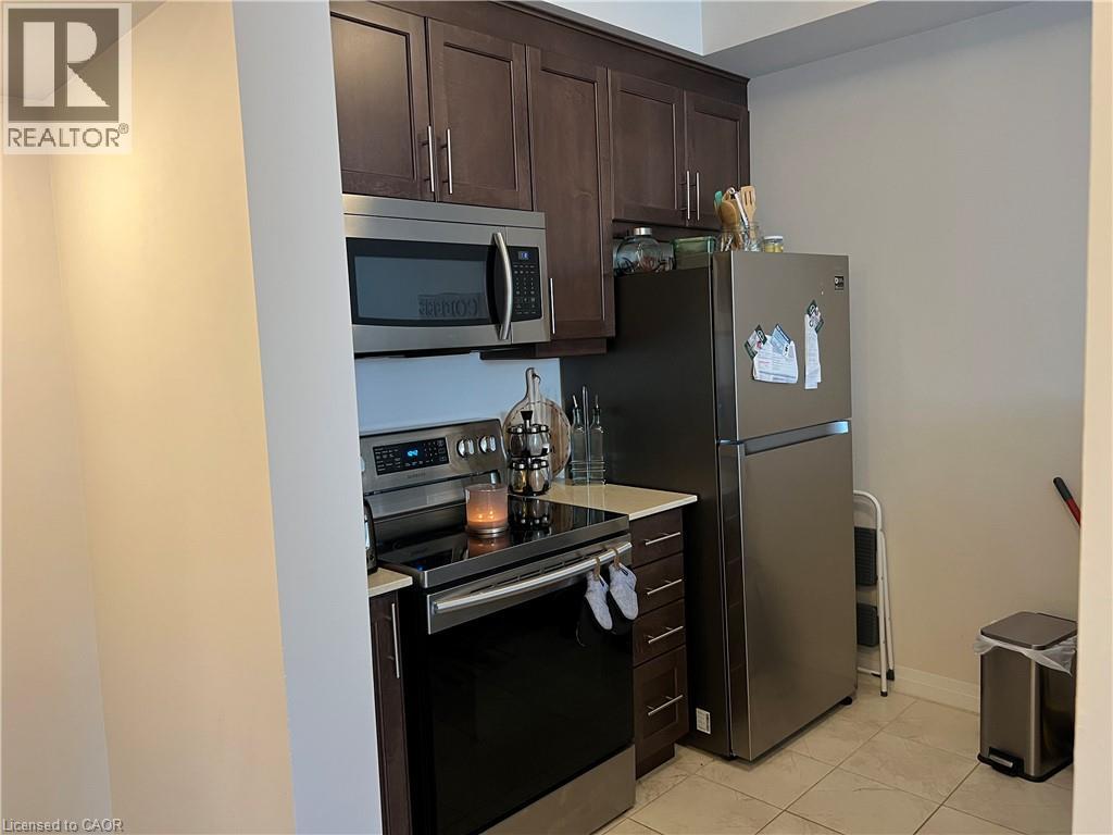 A kitchen with a refrigerator, microwave, oven, and cabinets.
