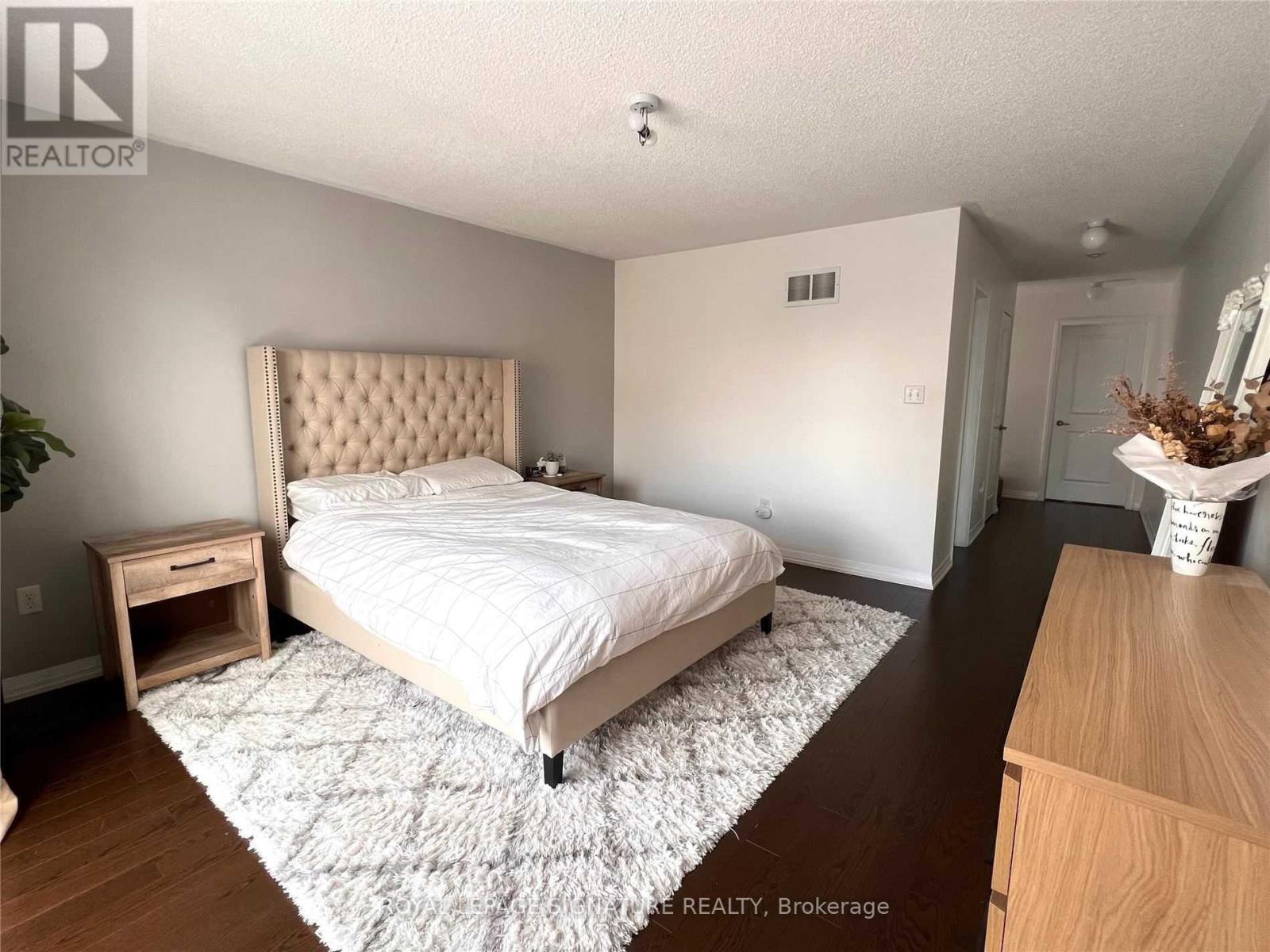 A bedroom with a large bed and a wooden dresser.
