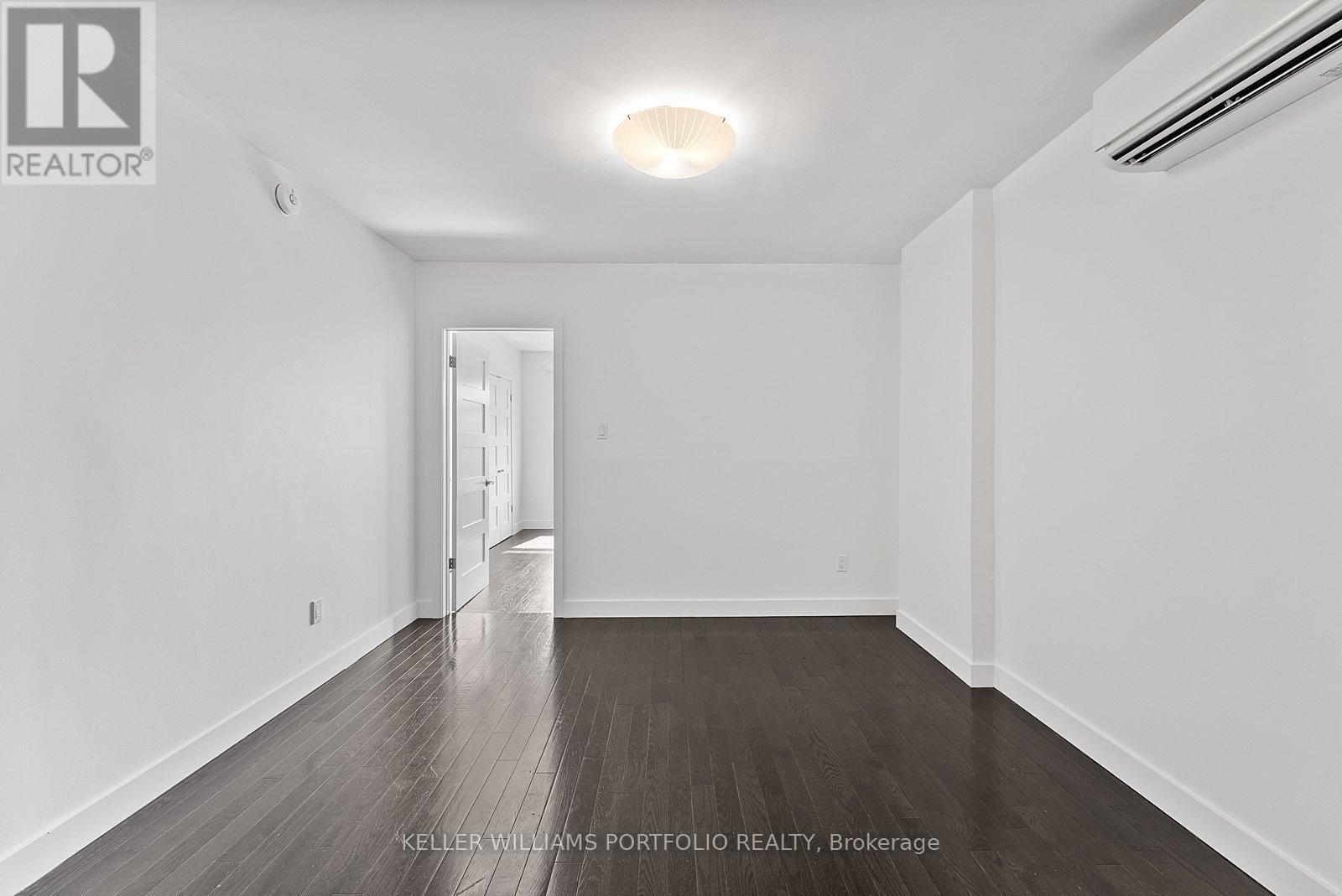 A spacious room with wooden flooring and white walls.