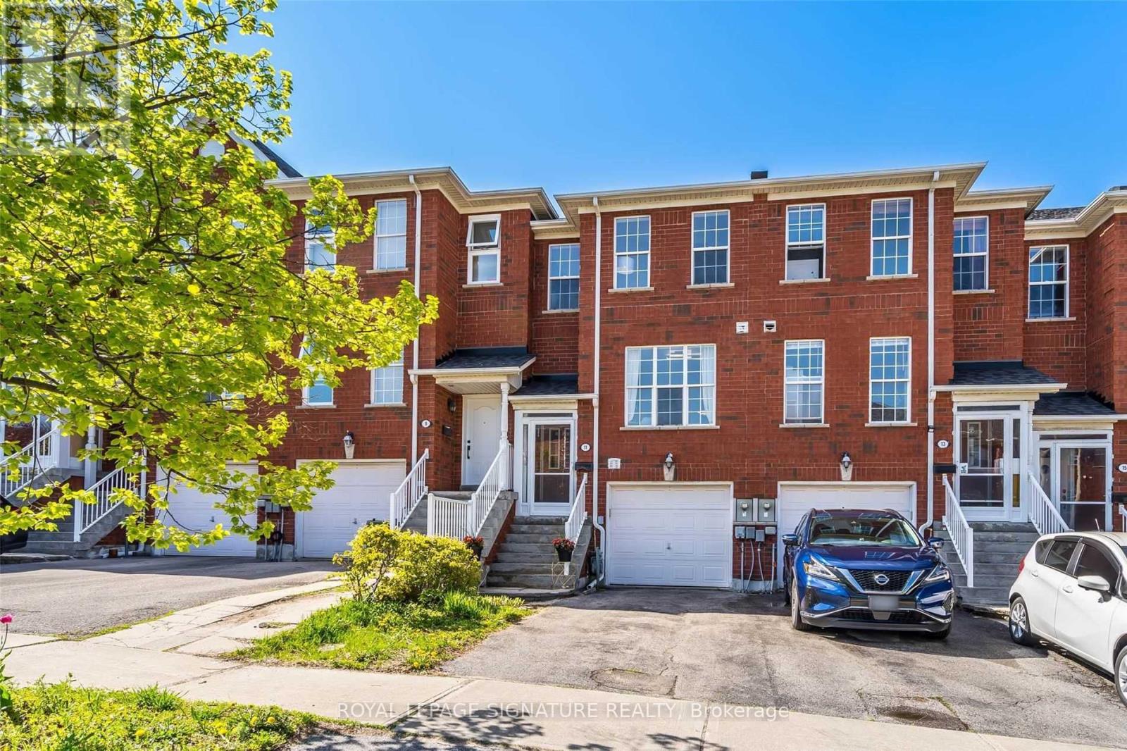 A row of red brick townhouses with cars parked in front.