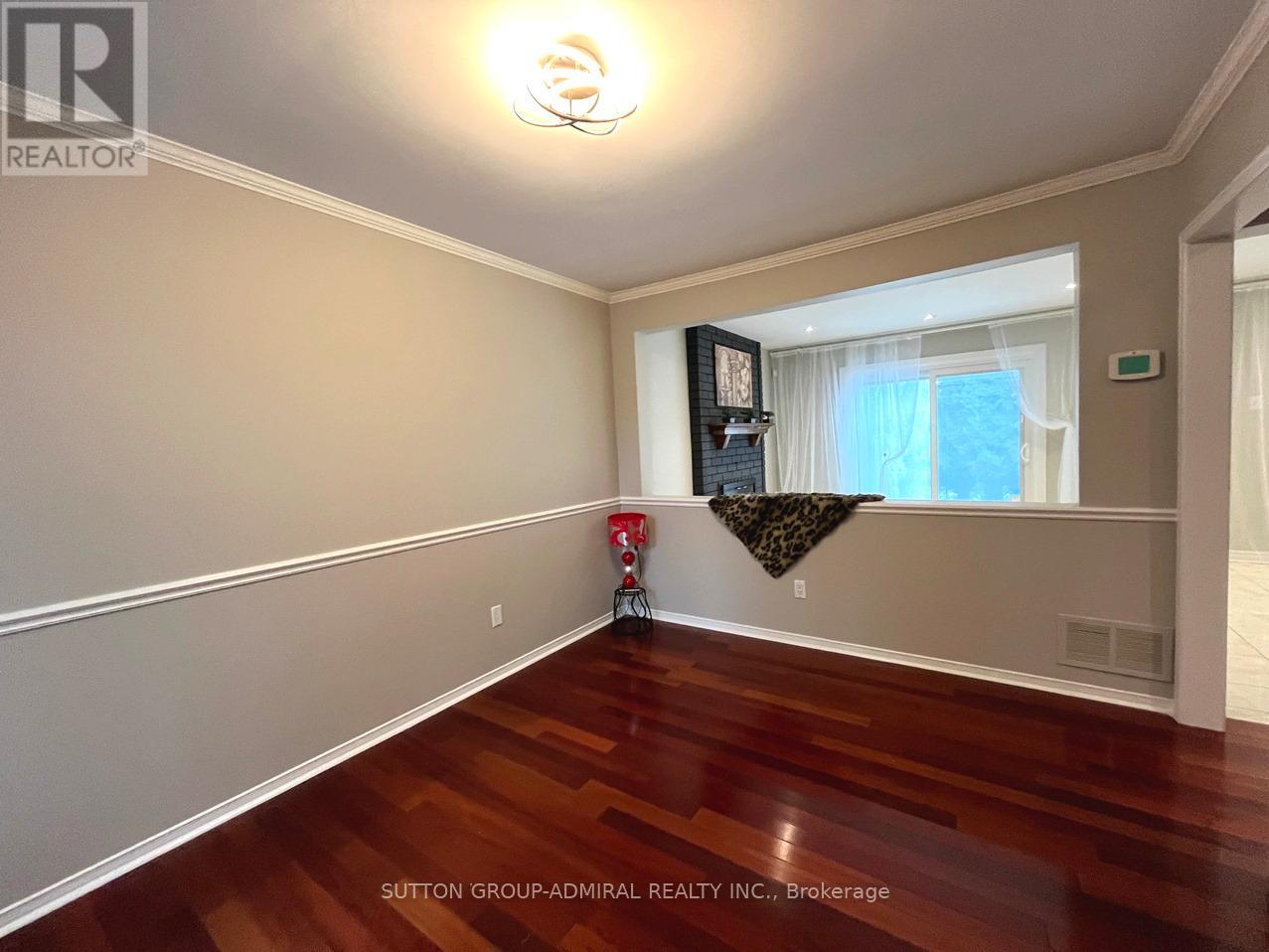 A room with wood flooring and a window with a view of trees.
