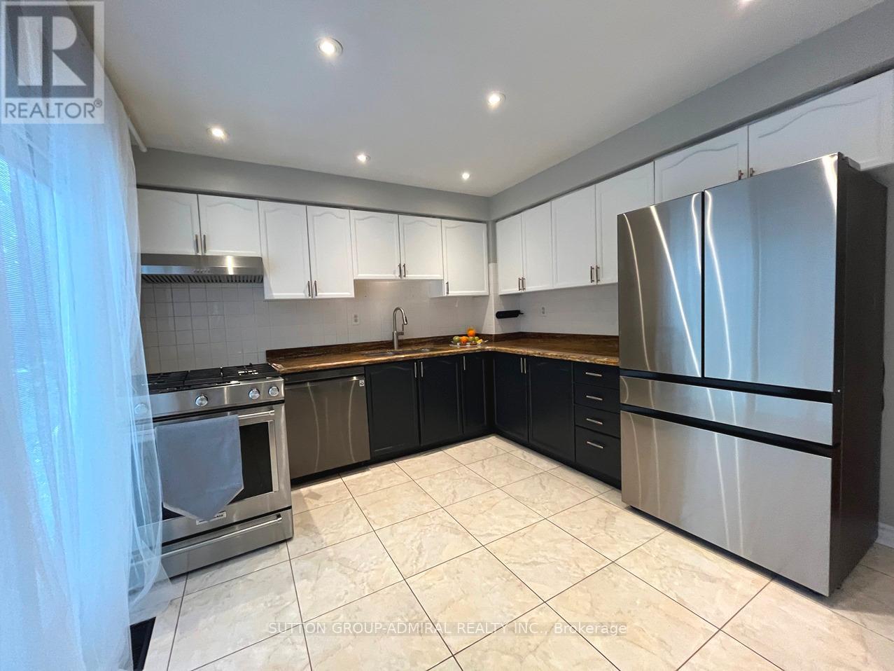 A modern kitchen with a stainless steel refrigerator and black cabinets.