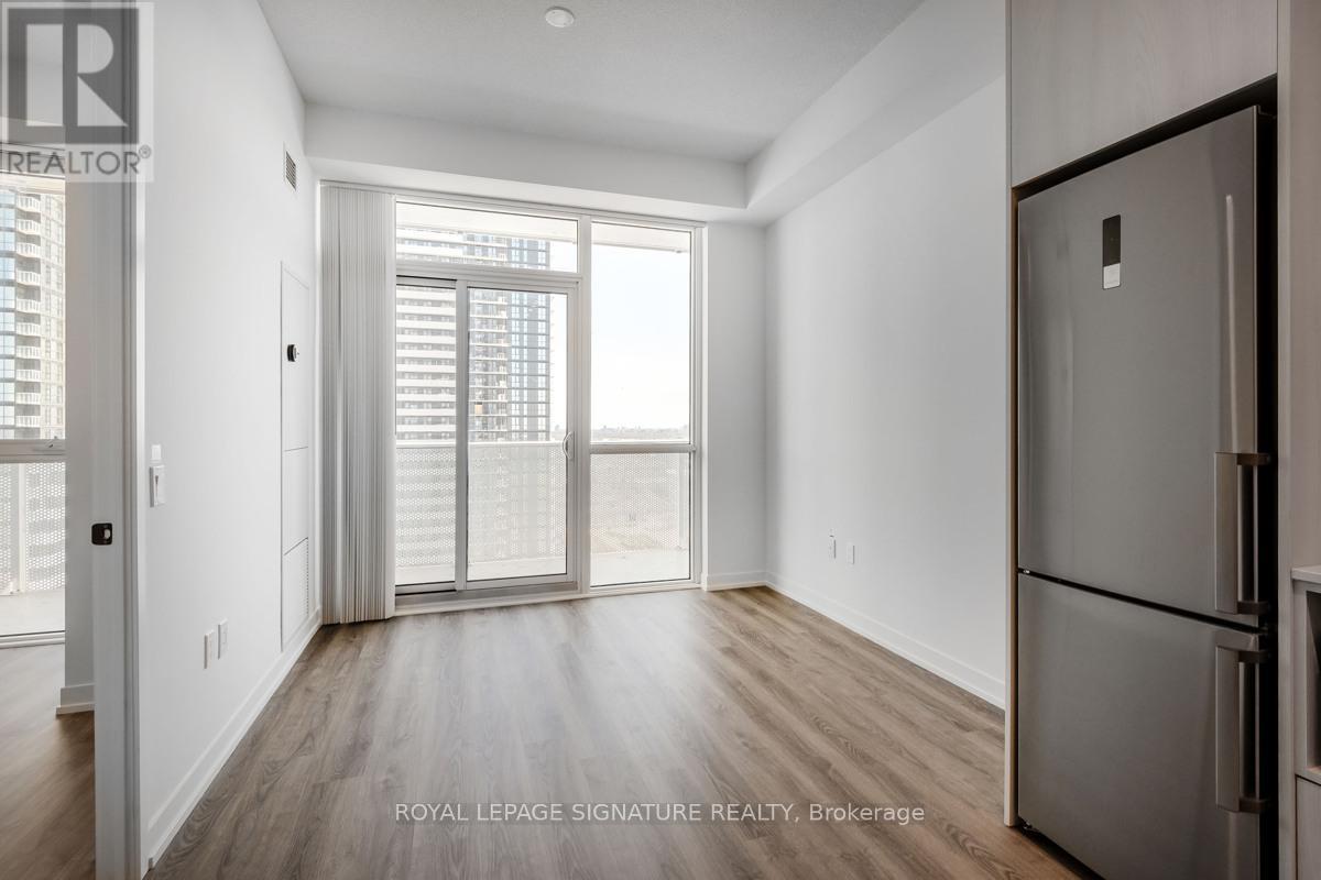 A spacious, empty room with a large window and a wooden floor.