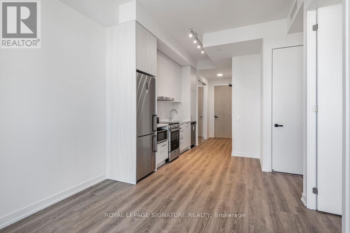 A spacious kitchen with white walls and wooden flooring.