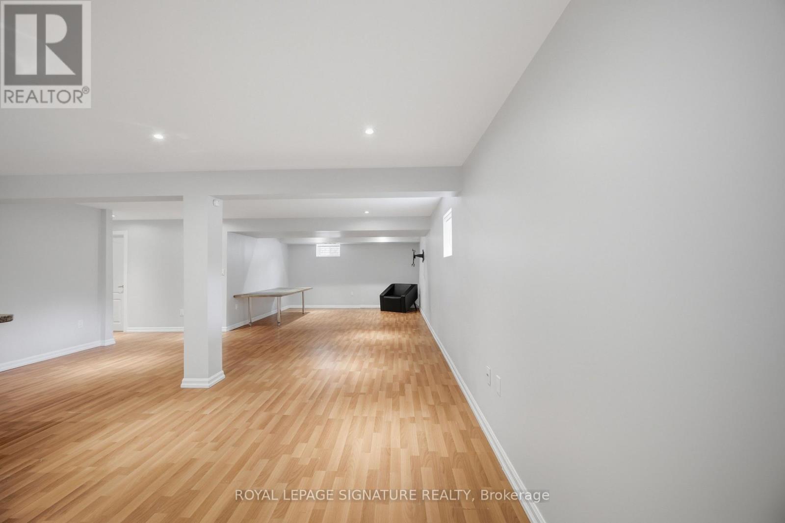 A spacious room with wooden flooring and white walls.