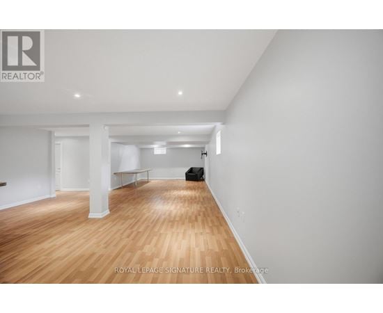 A spacious room with wooden flooring and white walls.