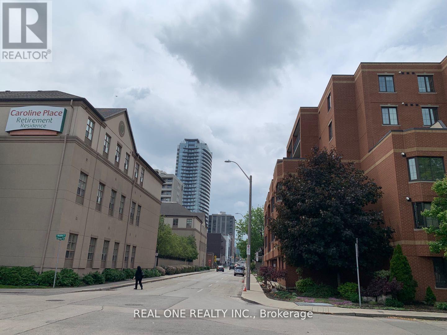 A street view of a residential area with apartment buildings and a sign for Caroline Place Retirement.