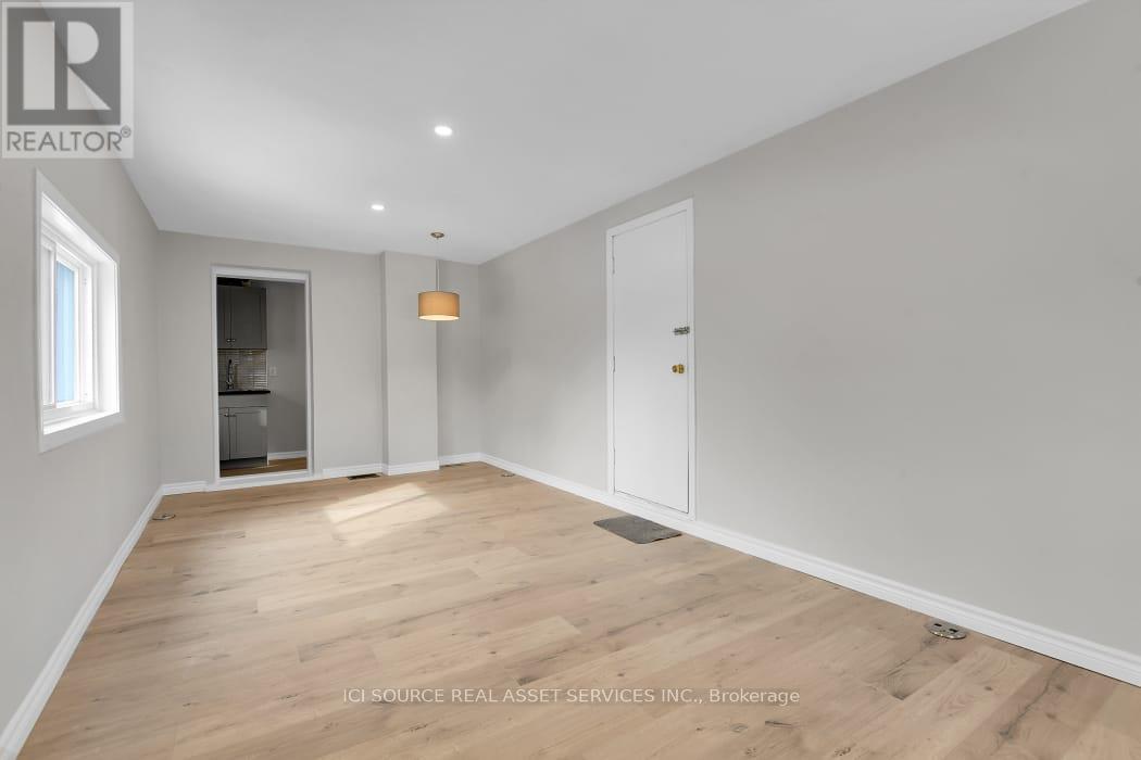 A spacious room with wooden flooring and white walls.