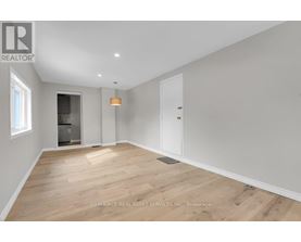 A spacious room with wooden flooring and white walls.