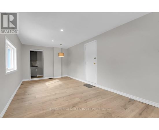 A spacious room with wooden flooring and white walls.