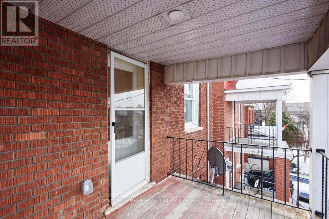 A balcony with a brick wall and a white door.