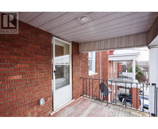 A balcony with a brick wall and a white door.