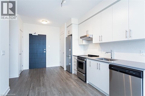 A kitchen with white cabinets and a black fridge.