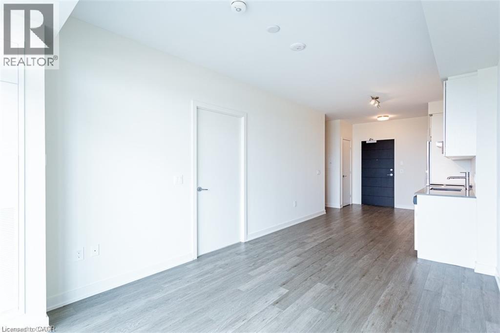A spacious room with wooden flooring and white walls.