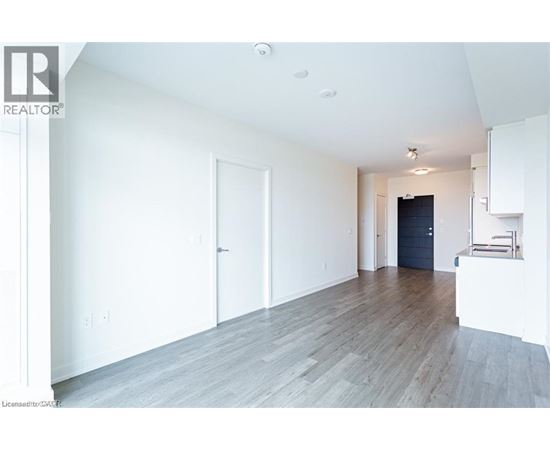 A spacious room with wooden flooring and white walls.