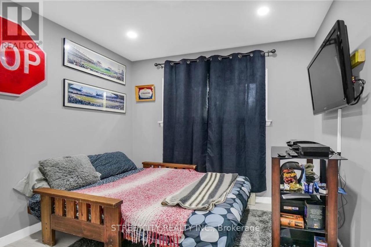 A bedroom with a bed, a television, and a window with curtains.