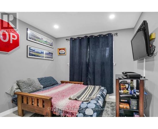 A bedroom with a bed, a television, and a window with curtains.
