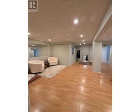 A spacious room with wooden flooring and a white chair.
