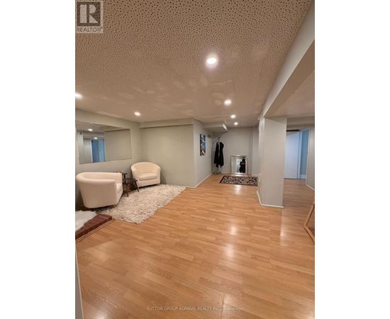 A spacious room with wooden flooring and a white chair.