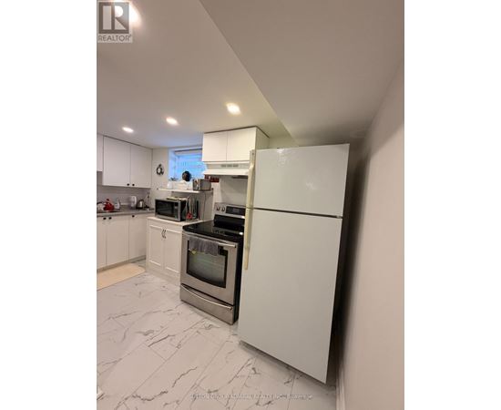 A white kitchen with a refrigerator on the right.