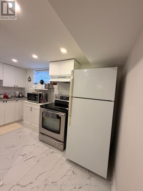 A white kitchen with a refrigerator on the right.
