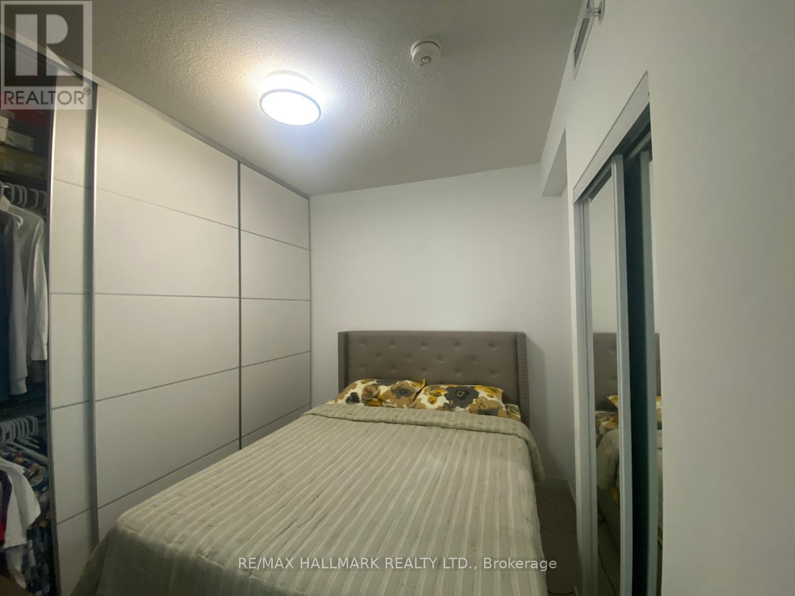 A bedroom with a bed and a wall-mounted light fixture.