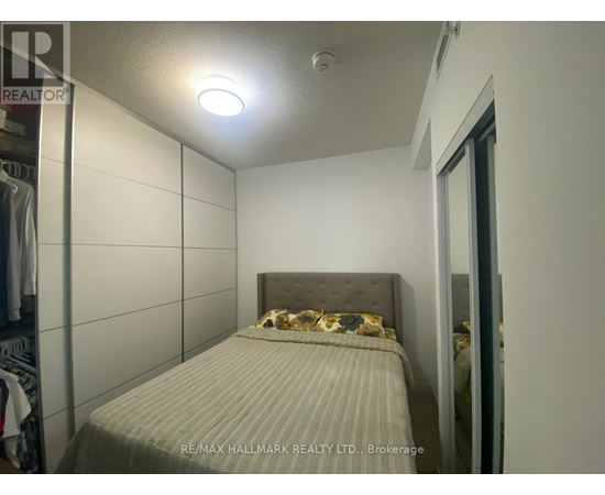 A bedroom with a bed and a wall-mounted light fixture.