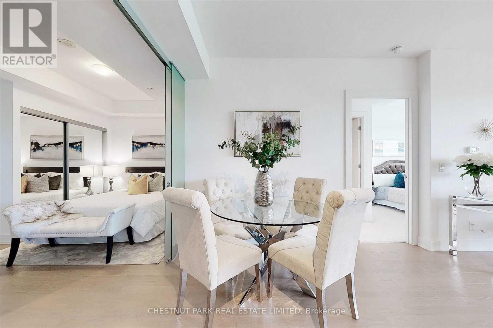 A modern dining room with a glass table and white chairs.